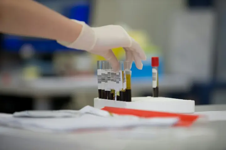 A gloved hand placing a sample tube into a rack